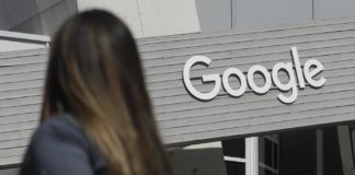 In this Sept. 24, 2019, file photo a woman walks below a Google sign on the campus in Mountain View, Calif. Australia’s government said on Tuesday, Feb. 16, 2021, it will amend draft laws that would make Google and Facebook pay for news to clarify that publishers would be paid in lump sums rather than per click on news article links.(AP Photo/Jeff Chiu, File)