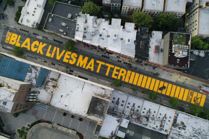 In this June 15, 2020, file photo, a giant "Black Lives Matter" sign is painted on Fulton Street in the Brooklyn borough of New York. A report released on Wednesday, Aug. 25, 2021 says 16% of American households donated to racial and social justice causes in 2020, resulting in a 3% uptick from 2019 as donors raced to provide support to affected communities in a year marked by protests and increased attention on racism in America. (AP Photo/John Minchillo, File)