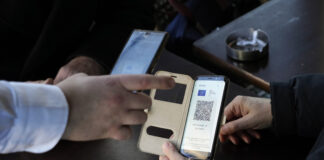 A waiter checks clients' vaccine pass in a restaurant, in Paris, Monday, Jan. 24, 2022. Unvaccinated people are no longer allowed in France's restaurants, bars, tourist sites and sports venues. A new law came into effect Monday requiring a "vaccine pass" that is central to the government's anti-virus strategy. (AP Photo/Thibault Camus)