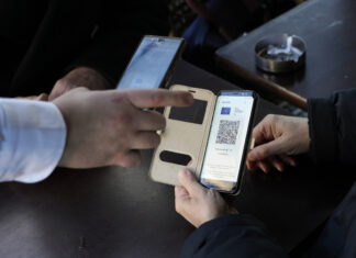A waiter checks clients' vaccine pass in a restaurant, in Paris, Monday, Jan. 24, 2022. Unvaccinated people are no longer allowed in France's restaurants, bars, tourist sites and sports venues. A new law came into effect Monday requiring a "vaccine pass" that is central to the government's anti-virus strategy. (AP Photo/Thibault Camus)