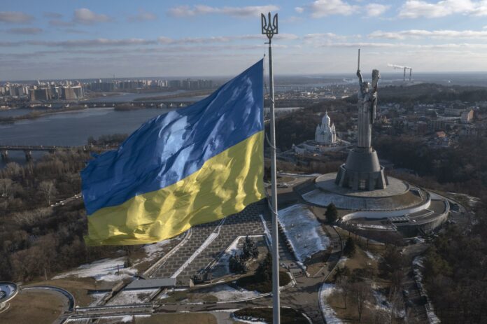 A view of Ukraine\'s national flag waves above the capital with the Motherland Monument on the right, in Kyiv Sunday, Feb. 13, 2022. Some airlines have halted or diverted flights to Ukraine amid heightened fears that an invasion by Russia is imminent despite intensive weekend talks between the Kremlin and the West. (AP Photo/Efrem Lukatsky)