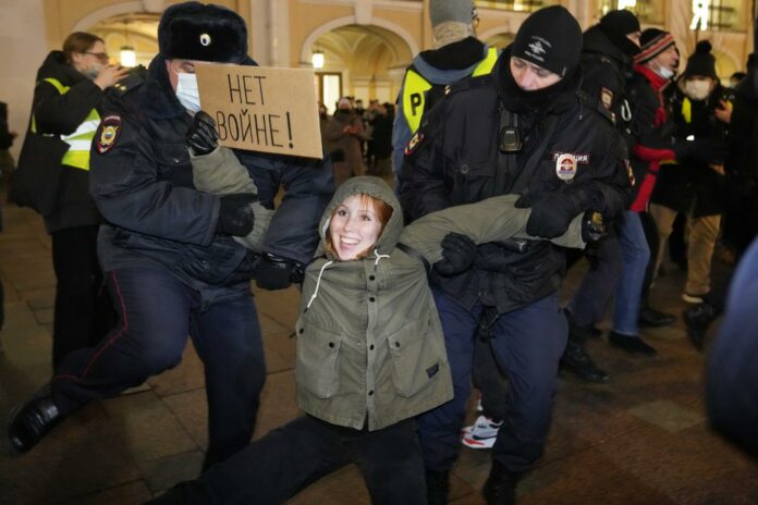 Police officers detain a demonstrator holding a sign reading \'No war!\' during an action against Russia\'s attack on Ukraine in St. Petersburg, Russia, Thursday, Feb. 24, 2022. Hundreds of people gathered in the center of Moscow on Thursday, protesting against Russia\'s attack on Ukraine. Many of the demonstrators were detained. Similar protests took place in other Russian cities, and activists were also arrested. (AP Photo/Dmitri Lovetsky)