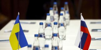Ukrainian and Russian national flags are placed on the table ahead of peace talks between Russian and Ukrainian delegations in a guest house in the Gomel region, Belarus is seen Monday, Feb. 28, 2022. The Russian and Ukrainian delegations met for their preliminary talks Monday. The meeting is taking place in Gomel region on the banks of the Pripyat River. (Sergei Kholodilin/BelTA Pool Photo via AP)