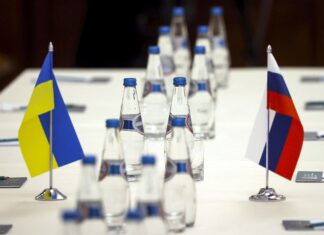 Ukrainian and Russian national flags are placed on the table ahead of peace talks between Russian and Ukrainian delegations in a guest house in the Gomel region, Belarus is seen Monday, Feb. 28, 2022. The Russian and Ukrainian delegations met for their preliminary talks Monday. The meeting is taking place in Gomel region on the banks of the Pripyat River. (Sergei Kholodilin/BelTA Pool Photo via AP)