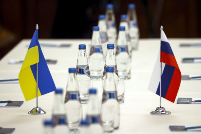Ukrainian and Russian national flags are placed on the table ahead of peace talks between Russian and Ukrainian delegations in a guest house in the Gomel region, Belarus is seen Monday, Feb. 28, 2022. The Russian and Ukrainian delegations met for their preliminary talks Monday. The meeting is taking place in Gomel region on the banks of the Pripyat River. (Sergei Kholodilin/BelTA Pool Photo via AP)