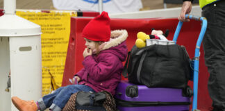 Milana Gudkovskaya, 3, sits on a trolley after fleeing the war from neighbouring Ukraine at the border crossing in Medyka, southeastern Poland, Wednesday, April 6, 2022. (AP Photo/Sergei Grits)